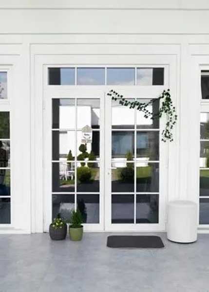 White French doors with grid-style glass panes, decorated with small potted plants and a trailing vine.