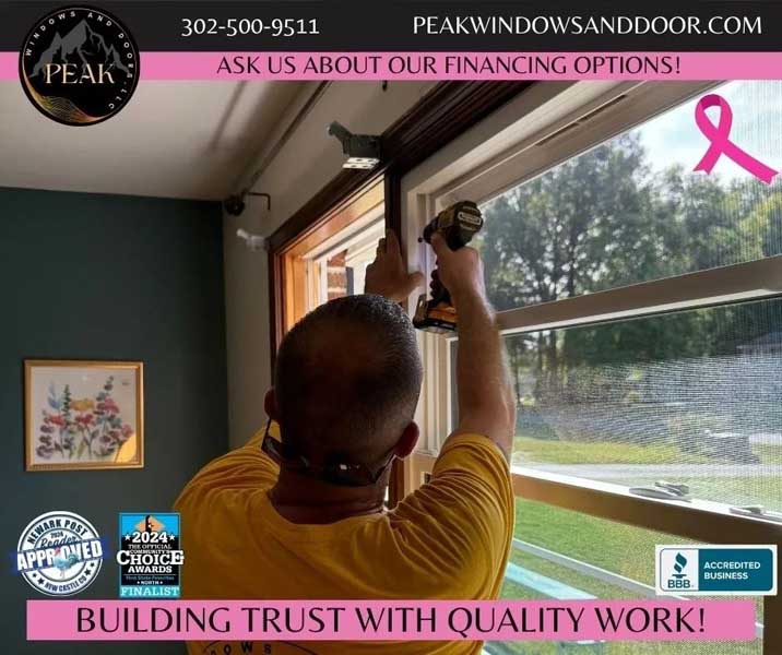 Person installing or adjusting a window frame using a power drill inside a room.