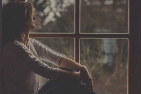 Person sitting by a window, silhouetted against an outdoor view.