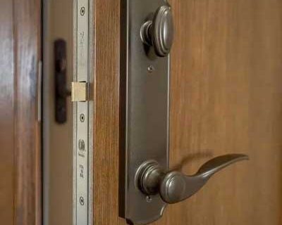 Close-up of a wooden door with a metal lever handle and lock hardware.