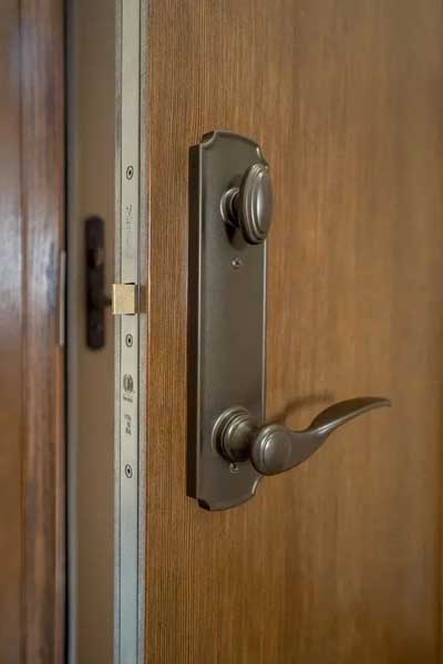 Close-up of a wooden door with a metal lever handle and lock hardware.